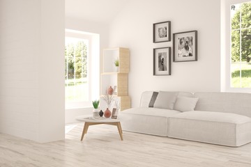 White room with sofa and green landscape in window. Scandinavian interior design