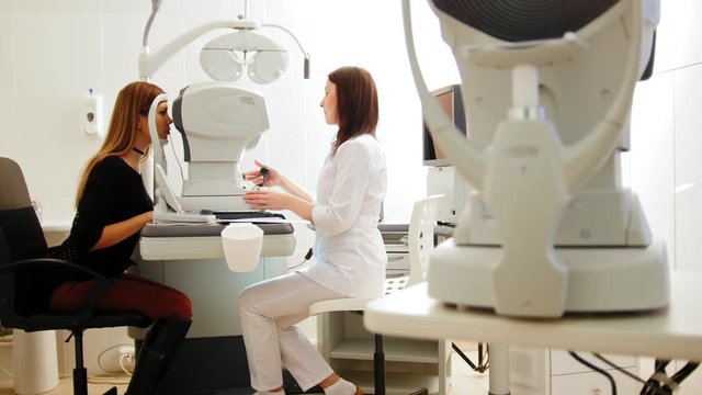 Modern ophthalmologist examining attractive woman's eyes with modern equipment, slider