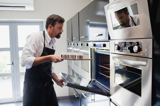 Chef putting tray into the oven.