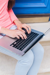 Student girl working with a laptop in front of blue doors