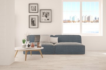 White room with sofa and urban landscape in window. Scandinavian interior design
