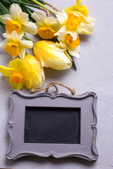 Yellow flowers  and empty frame on grey textured background.