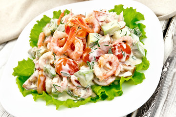 Salad with shrimp and avocado in plate on board
