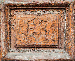 Old wooden door with carved overgrown with wild grapes