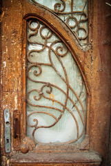 Old wooden door with carved overgrown with wild grapes