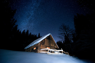 Beautiful wooden house in the winter forest under the stars