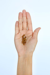 A hand of a woman with some lozenge pills on white background