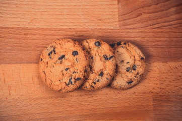 Home made chocolate cookies on wooden background. Crispy chip biscuits with chocolate and hazelnuts. Delicious fresh chocolate chip cookies.