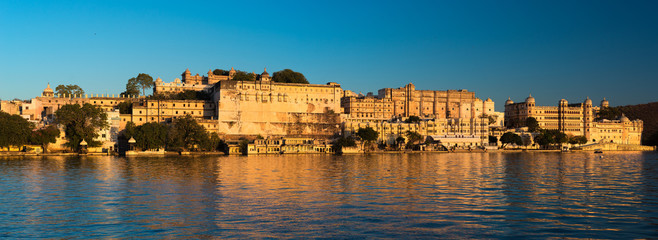Udaipur cityscape at sunset. The majestic city palace on Lake Pichola, travel destination in Rajasthan, India
