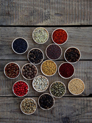 spices on a wooden background. Coriander, black pepper, paprika, mustard, turmeric, cumin, sumac, fenugreek, cloves, cubeb.
