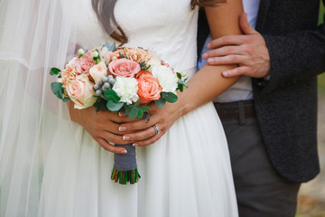 Wedding bouquet in bride hands standing next to groom