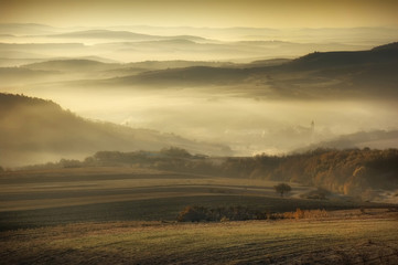 Fototapeta na wymiar Misty morning landscape. Fog and hills in sunrise light, natural scenery