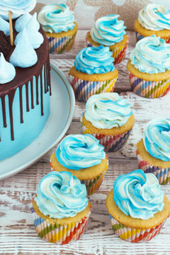 Children's blue cake and cupcakes rainbow color on a white background with meringue