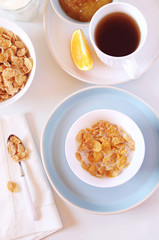 Сorn flakes in bowl,  milk and cup of tea