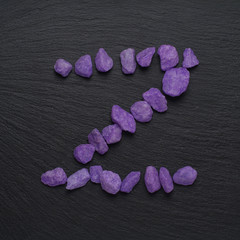 Letter Z made from purple stones on a dark background,