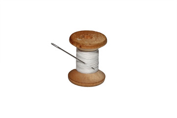 old wooden spool of white thread and a metallic needle on a white isolated background