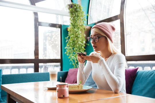 Woman taking pictures of food with mobile phone in cafe