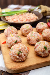 Raw meat balls, ready for cooking on a cutting board.