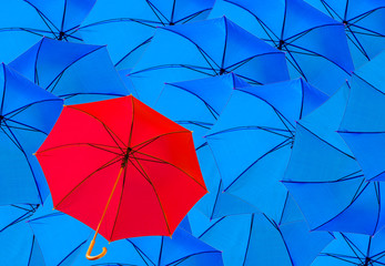 parasol rouge sur fond de parasols bleus.