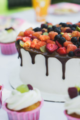 Delicious fruit cake with cupcakes for a happy birthday