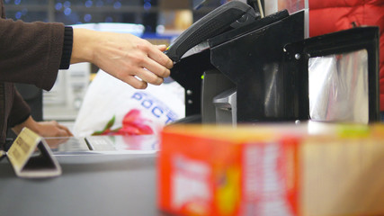 Shopper paying for products at checkout. Foods on conveyor belt at the supermarket. Cash desk with cashier and terminal in hypermarket. Working of cashier. Shopping at store. Close up