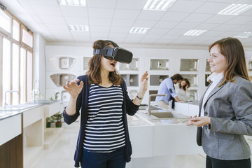 Customers consulting saleswoman in shop for kitchen sinks