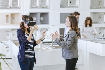 Customers consulting saleswoman in shop for kitchen sinks