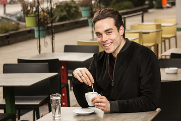 young man happy smiling, looking at camera, coffee cup