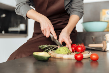 Cropped picture of young lady cut the avocado