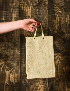 golden shopping bag in female hand on wooden background