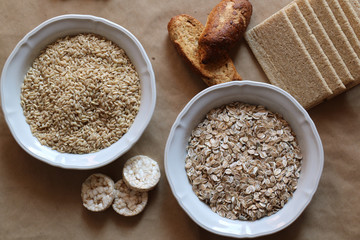 Oats and rice in a bowl. Rice cakes and bread in background. Food high in carbohydrates.