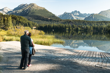 healthy and vital senior couple standing on hike and watching beautiful mountain view