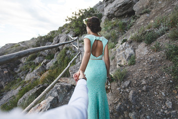 The bride and groom on nature in the mountains near the water. Suit and dress color Tiffany. Walk hand in hand.