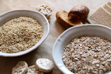 Oats and rice in a bowl. Rice cakes and bread in background.