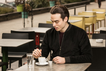 young man stirring coffee cup table