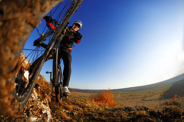 Fototapeta na wymiar Man on mountain bike on the background of beautiful sunset. Bicycle wheel closeup.