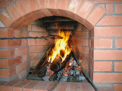 cozy fireplace of brick in the house preparing sausage on a branch