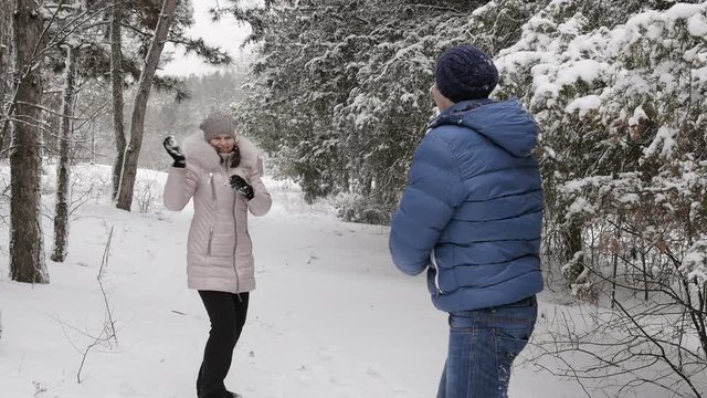 Couple having snowball fight in snow in winter forest