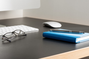 Pen on Notebook and Eyeglasses by a Computer on Office Table