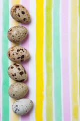 Quail eggs on striped colorful watercolor background. Easter celebration concept