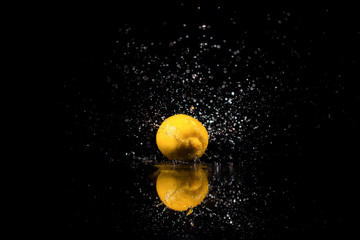 Fototapeta na wymiar The lemon with drops stands on the black background