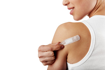 Smiling woman taking off adhesive bandage from healed arm. 