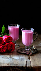 Healthy berry smoothie with red roses on a wooden background.