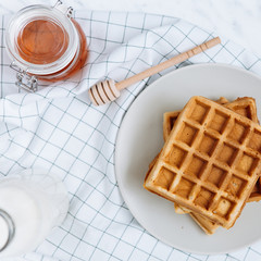 Homemade Belgian Waffles with milk and honey on table. Delicious breakfast