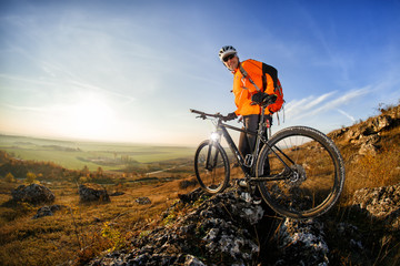 Cyclist on the top of a hill with blue sky clouds