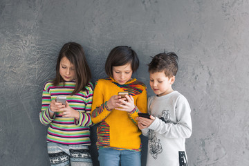 Group of young girls and a boy playing in the phone, smiling and laughing.