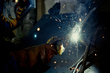 Man welding steel in an industrial background - obrazy, fototapety, plakaty