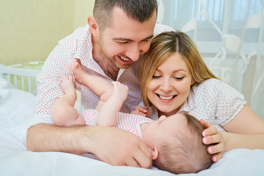 Mother father and baby playing on the bed. The concept of a happy family.