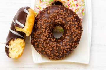Tasty donuts with icing and chocolate on white wooden background, copy space
