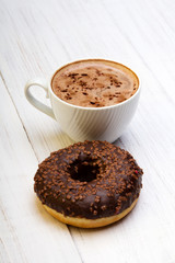 Cup of coffee and tasty donuts with icing and chocolate on white wooden background, copy space